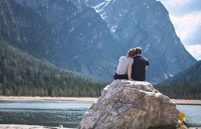 美しい川辺にそびえ立つ大きな岩の上で寄り添うカップル