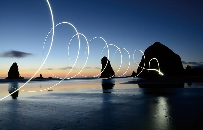 海岸に並ぶ岩から円を描く光線がビームのように発信されていく幻想的な映像