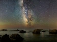 夜の海岸で満開に広がる星とオーロラ