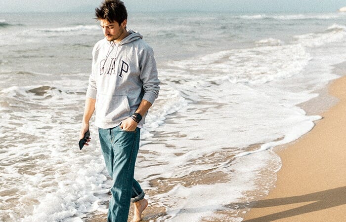 スマホ片手に海岸をはだしで歩く一人の男性