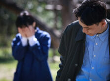 公園で彼氏に別れを告げられ両手で顔を覆い悲しむ女性