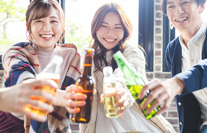 笑顔でビール片手に乾杯する男女3人